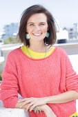 A young woman wearing large earrings, a fuchsia jumper and a yellow top