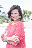 A young woman wearing large earrings, a fuchsia jumper and a yellow top