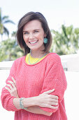 A young woman wearing large earrings, a fuchsia jumper and a yellow top