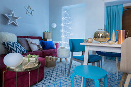 Blauer weihnachtlich dekorierter Wohnraum mit Esstisch und rotem Sofa