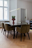 Upholstered chairs around modern dining table in kitchen-dining room with parquet floor