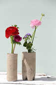 Selbstgemachte Vasen aus Beton mit Ranunkeln, Ageratum und Anemone
