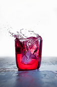 A red drink splashing against a white background