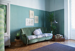 Vintage velvet sofa against green wall in corner of period apartment