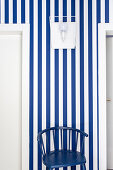 Dark blue chair against blue-and-white striped wallpaper