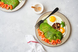 Healthy breakfast with fried eggs, salmon and avocado