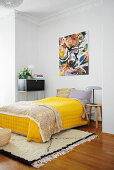 Yellow bedspread on double bed below modern painting in bedroom