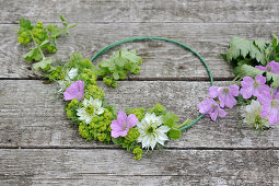 Tie a summer wreath of lady's mantle, cranesbill, and maiden in the countryside on a wire ring