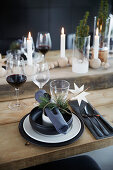 Candles, glass and wooden baubles on festively set wooden table