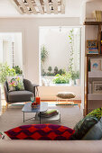 Grey armchair with scatter cushion, stool and coffee table in front of TV in living room