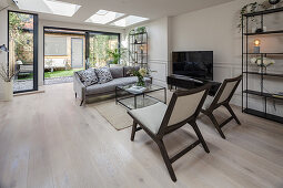 Seating area around TV in living room with skylights and glass wall overlooking garden