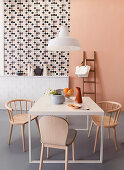 Pastel-pink wall, wallpaper with graphic pattern and tiled dado in dining room