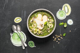A green bowl with apple, pear, cucumber and kiwi
