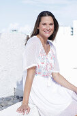 Langhaarige Frau in weißem Sommerkleid mit bunter Stickerei