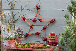 Star made of cinnamon sticks with cones, ball and candle Christmas decoration