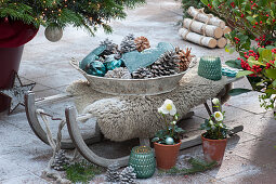 Bowl with hearts, cones and balls as a Christmas decoration on a wooden sledge with fur