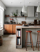 Bar stools at counter in open-plan kitchen in earthy shades