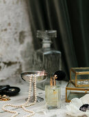 Perfume, jewellery box and pearl necklace on dressing table