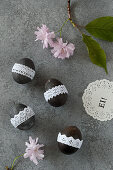 Blown eggs painted black and decorated with lace ribbon
