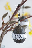 Blown egg painted black and decorated with lace ribbon