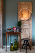 Wreath with candle on old wooden door next to table and stool