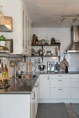 Country-house kitchen with stainless steel worksurfaces and white cabinets