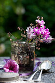 Sträußchen aus Lichtnelke, Wegerichblüten und Plattährengras in alter Teedose, Petunien-Blüte, Löffel