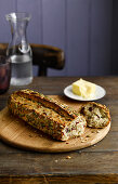 Seeded bread, broken, on a wooden plate with butter