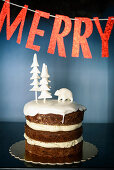 Layer cake decorated with wintry fondant icing below festive banner