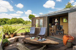 Rustikale Terrasse mit Couchtisch und Liegestühlen am Tiny Home