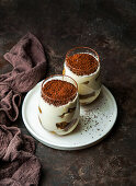 Rraditional coffee flavored dessert tiramisu served in glass cup on table