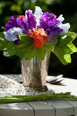 Posy of sweet peas and lady's mantle leaves in silver vase