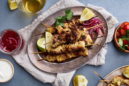 Marinated chicken skewers with pickled onions, tomato salad, lemon and yoghurt sauce