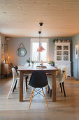 Various chairs around wooden table in dining room of modern country house