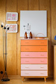 Chest of drawers with drawers in colour gradient against wood-panelled walls