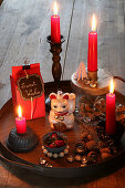 Festive arrangement with red candles and Maneki-neko cat on tray