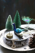 Winter arrangement of peacock figurine and miniature trees on metal plates