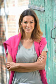 A young woman wearing a grey T-shirt with a pink jumper over her shoulders