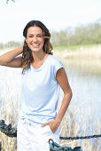 A young woman wearing a light-blue T-shirt and white shorts near river