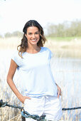 A young woman wearing a light-blue T-shirt and white shorts near river