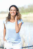 Junge Frau in hellblauem T-Shirt und weißen Shorts am Fluss