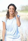 A young woman wearing a light-blue T-shirt and white shorts near river