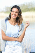 A young woman wearing a light-blue T-shirt with a jumper over her shoulders and white shorts near river