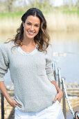 A young woman wearing a grey jumper near river