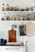 Storage jars on two shelves with hooks below in kitchen