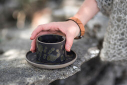 Frauenhand mit Armband hält Becher