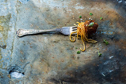 Spaghetti mit Fleischbällchen aufgespießt auf einer Gabel