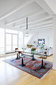 Swivel chairs at glass table in open-plan interior with exposed, white ceiling beams