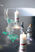Candles, porcelain and glass figures on festively painted table