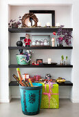 Basket of wrapping paper and wrapped gift in front of shelves in niche